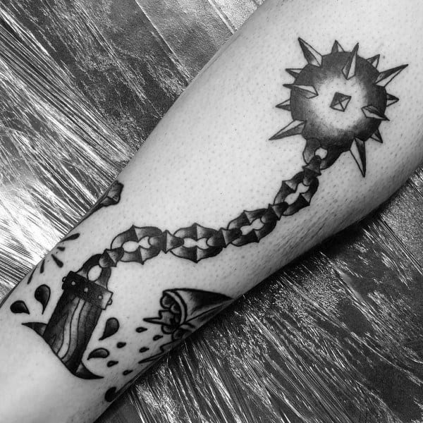 Black and gray mace tattoo with a spiked ball on a chain, striking with force, symbolizing power, resilience, and medieval weaponry.