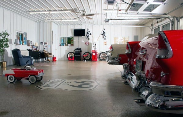 A vintage-themed garage with classic cars, a Route 66 sign on the floor, and a small red toy car