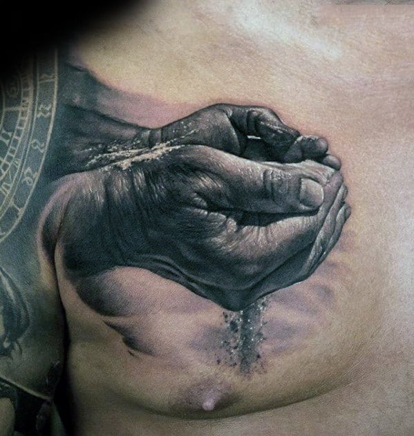 Realistic tattoo of hands holding sand on a person's chest