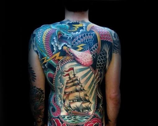 Man's back adorned with colorful tattoo of dragon, bird, and sailing ship