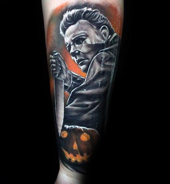Michael Myers tattoo with a menacing pose, bloody knife, and glowing jack-o'-lantern, set against an eerie orange background.