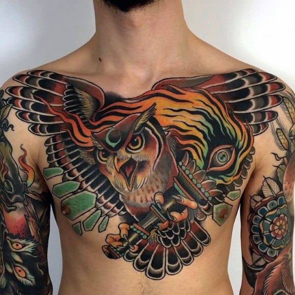 Neo-traditional owl chest tattoo with bold colors, outstretched wings, and fierce details, blending tribal and fantasy elements.