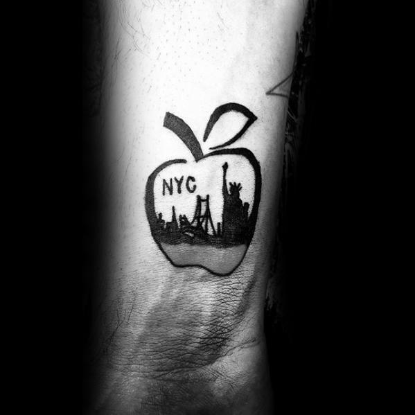 Small black tattoo of an apple silhouette with “NYC” text and New York City skyline inside, including the Statue of Liberty.