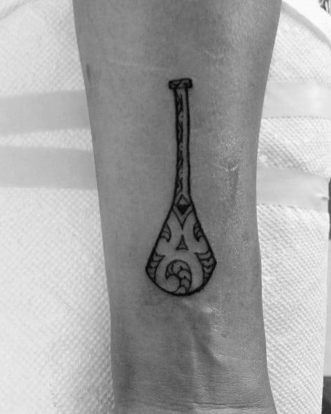 Paddle tattoo with tribal-inspired patterns on the forearm, symbolizing strength, adventure, and connection to water.