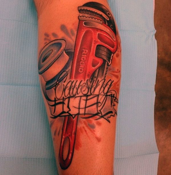 Tattoo of a red pipe wrench, plumber's tape, and graffiti-style text reading Causing It with dynamic shading and bold colors.