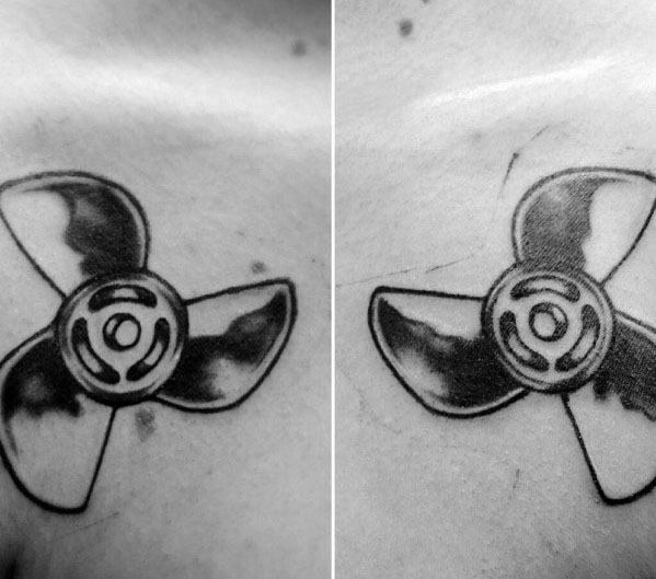 Simple black and grey tattoo of a three-blade propeller on the chest, with bold outlines and shaded details for a classic mechanical look.