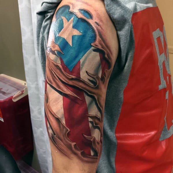 Puerto Rican flag tattoo with a 3D ripped skin effect on the upper arm, revealing bold red, white, and blue colors with a striking star.