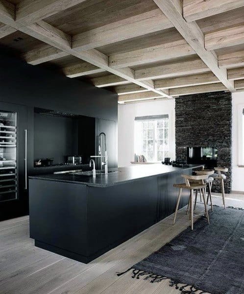 Modern rustic kitchen with a sleek black island, wooden beam ceiling, and minimalist decor.