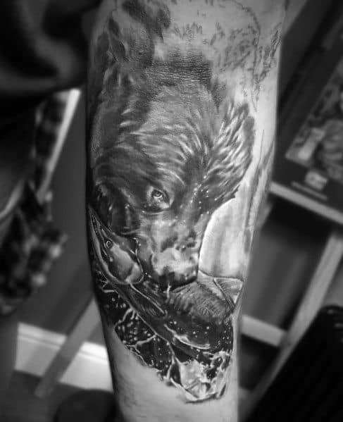 Realistic black and grey tattoo of a bear catching a salmon, symbolizing strength and survival, covering the forearm with intricate details.