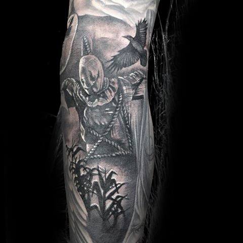 Realistic scarecrow tattoo in a moonlit cornfield with a stitched face, crows, and eerie shading in black and grey ink.