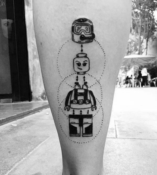 Black line tattoo of a LEGO-style scuba diver figure on the calf, shown in separated parts with dotted guide lines.
