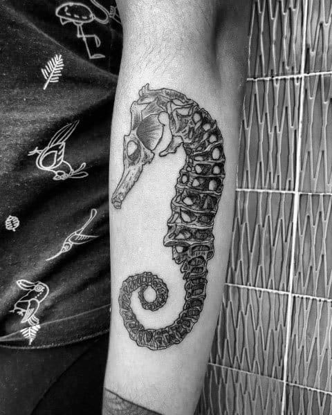 Realistic seahorse skeleton tattoo on forearm, featuring intricate bone details and shading for a bold and striking design.