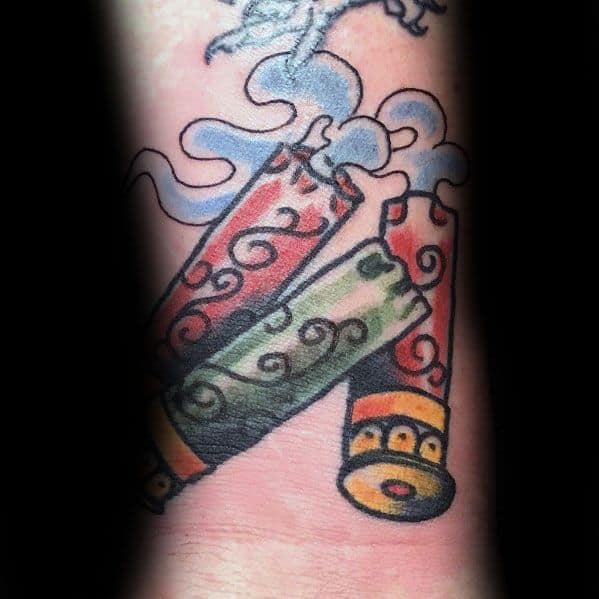 Colorful shotgun shell tattoo with swirling smoke details, featuring ornate red and green patterns on the casings for a bold design.