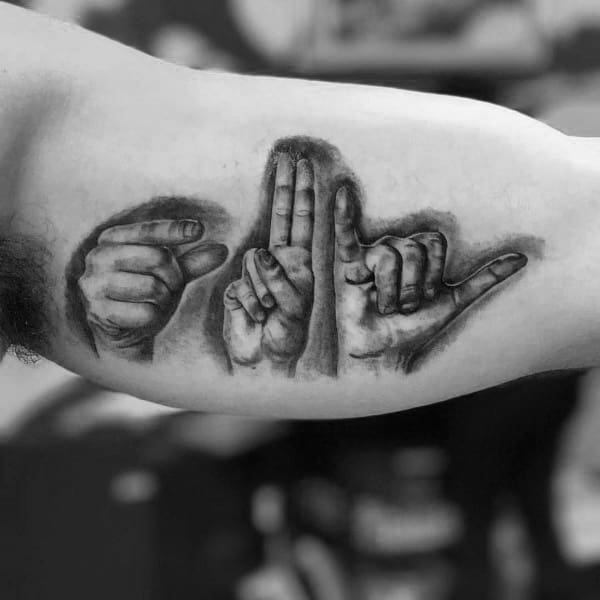 realistic black and grey tattoo of hands signing "LOVE" in American Sign Language, placed on the bicep with detailed shading for depth