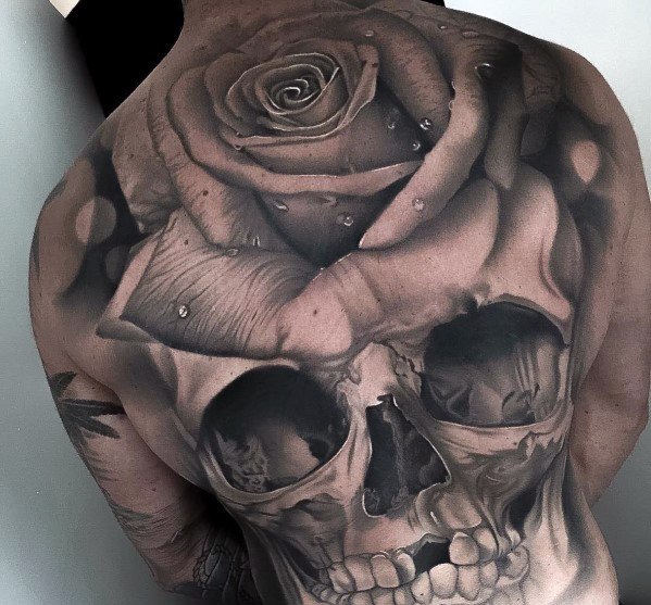 Realistic skull back tattoo seamlessly blended with a blooming rose, featuring intricate shading and water droplet details.