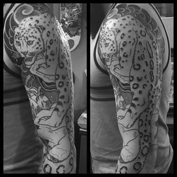 Full-sleeve snow leopard tattoo in black and gray, showcasing the feline climbing with detailed fur patterns and swirling background.