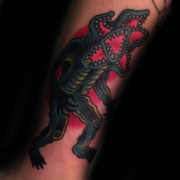 Bold tattoo of the Demogorgon from Stranger Things in a stylized, graphic design with sharp teeth and a red background glow.