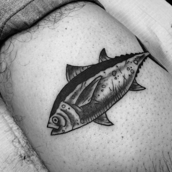 Black and grey tuna fish tattoo on a man's leg, featuring bold outlines and shading for a traditional, rugged look.