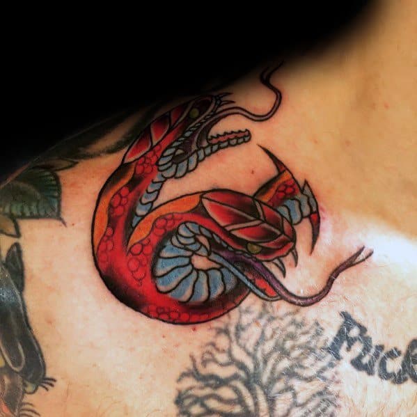 Two-headed snake tattoo in bold red, black, and blue tones, coiled with open jaws, placed on the shoulder for a fierce look.