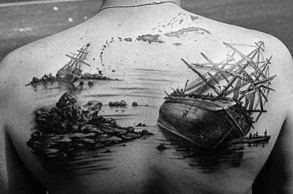 Realistic black and grey back tattoo of two shipwrecks near rocky shores, with intricate water reflections and detailed rigging.