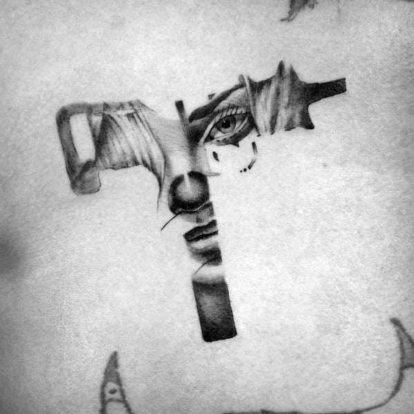 Surreal Uzi tattoo blending a realistic face with the firearm design. Intricate shading and fine details create a striking visual.