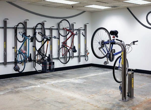 Bike storage room with vertical wall racks and a bike repair stand on a concrete floor.