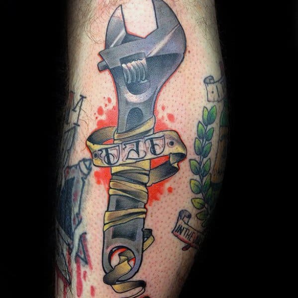 Tattoo of an adjustable wrench wrapped in a yellow ribbon with the word DAD, set against a red splatter-style background.