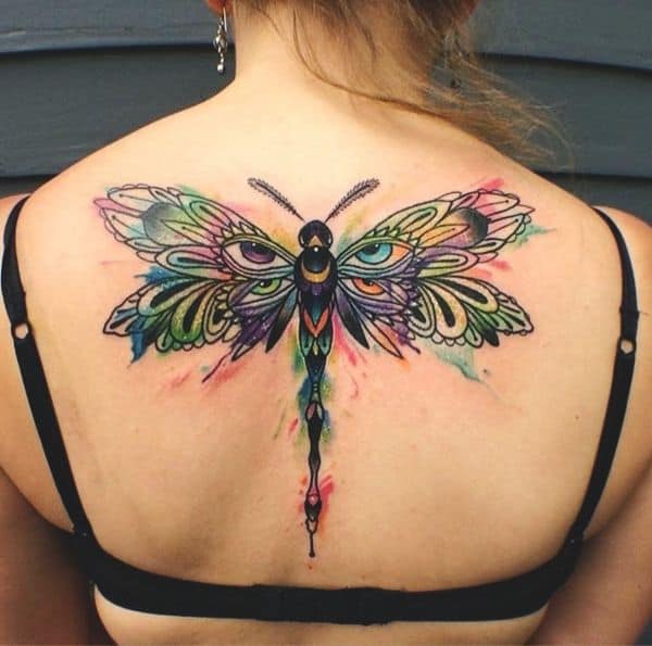 Vibrant watercolor dragonfly tattoo on the upper back, featuring intricate patterns and bold splashes of color for a striking look.