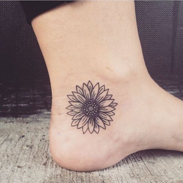 Minimalist black ink sunflower tattoo on the ankle with clean line work and symmetrical petals for a simple yet elegant design.