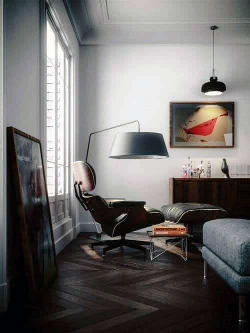 Modern office space with Eames lounge chair, floor lamp, and abstract wall art in a minimalist room.
