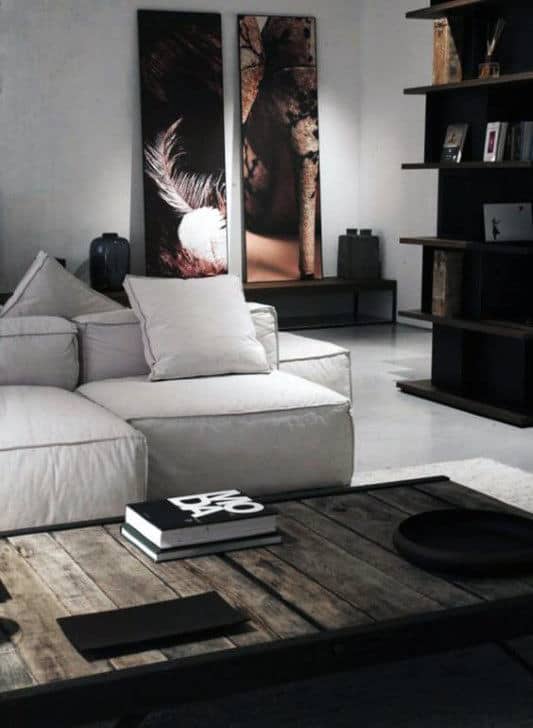 Modern living room with neutral sofa, abstract artwork, and dark wood shelving.