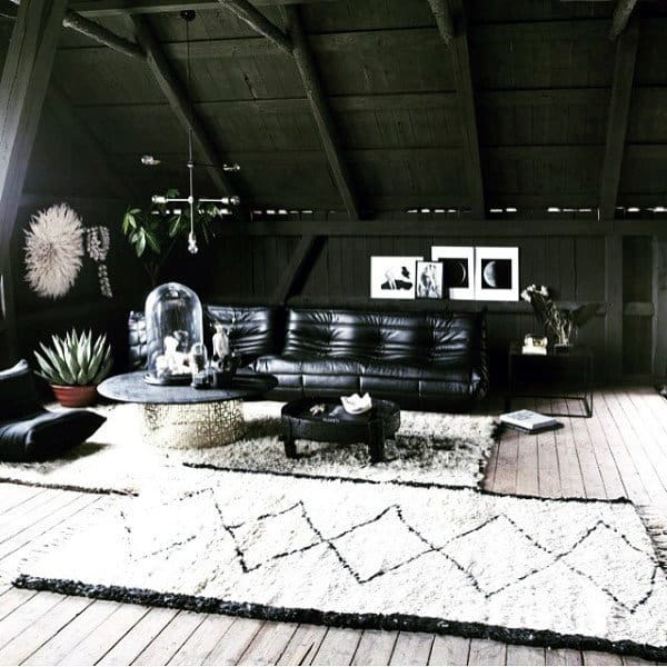 Loft living room with black leather sofa, wooden ceiling beams, and modern decor accents.