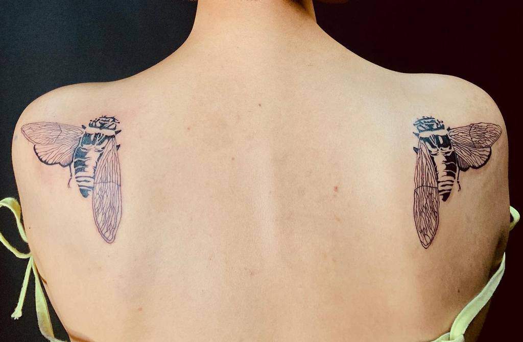 Back tattoos of two cicadas, one on each shoulder
