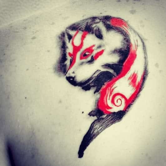 Tattoo of a stylized wolf with red and black accents, inspired by Japanese art