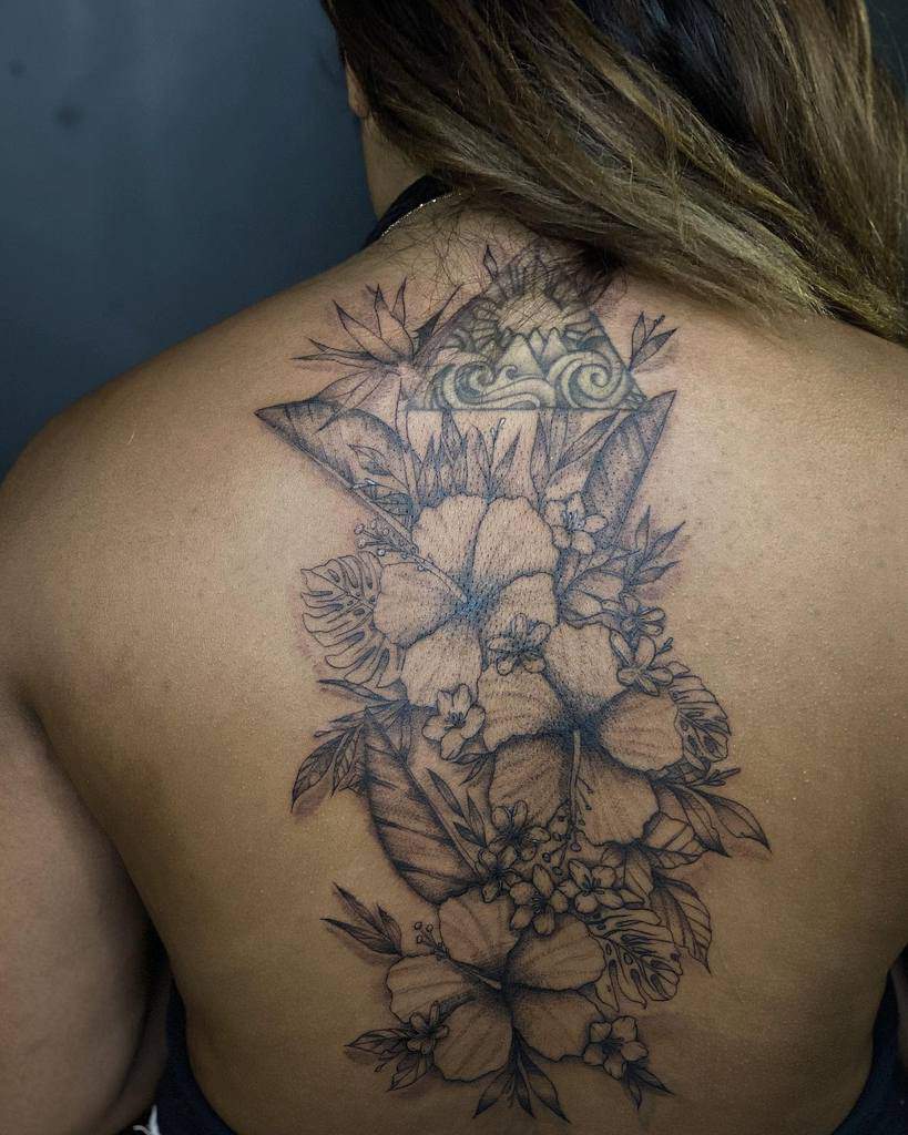 Detailed blackwork Plumeria flower tattoo covering the upper and mid-back, incorporating intricate leaves and tribal-inspired geometric accents for a bold yet elegant design
