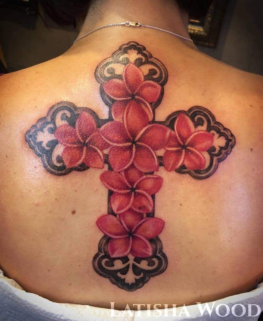 Intricate Plumeria tattoo forming a cross shape on the upper back, featuring vibrant red flowers with bold black decorative details, blending floral elegance with spiritual symbolism