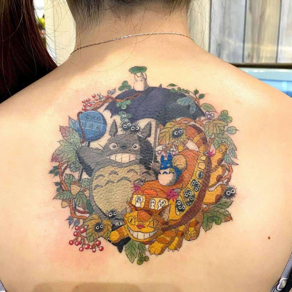 Vibrant Totoro tattoo on the upper back featuring Totoro, Catbus, forest sprites, and lush foliage, creating a circular Ghibli-inspired scene