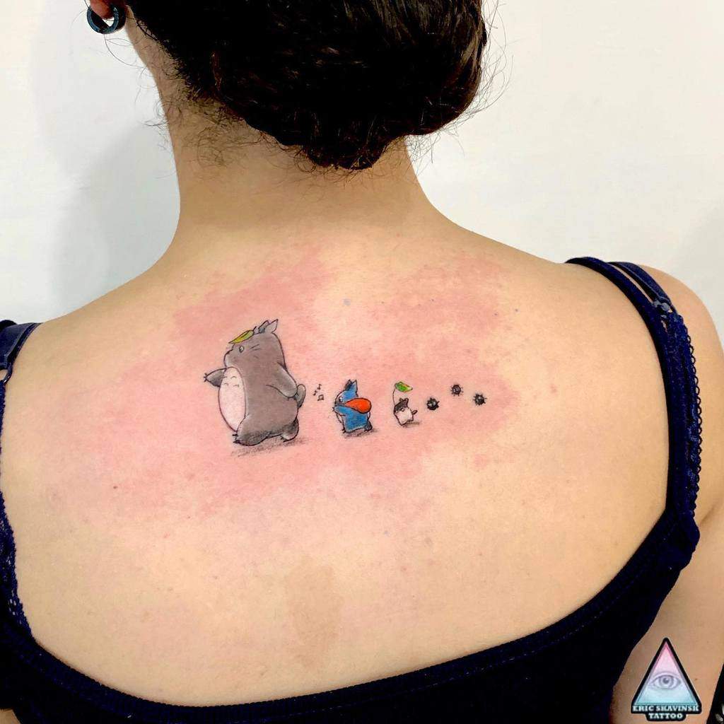 Minimalist Totoro tattoo on the upper back, featuring Totoro and his small companions walking in a line with soot sprites
