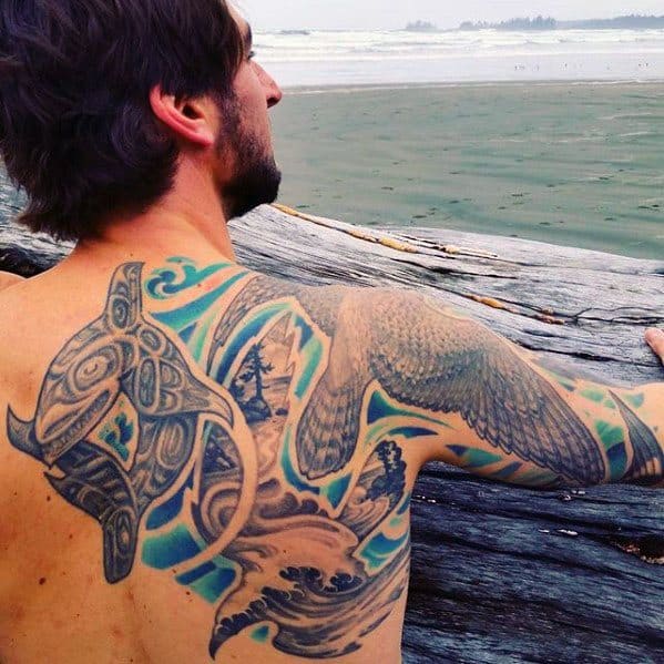 Vibrant and detailed orca tattoo on the back and shoulder, combining tribal designs with waves and bird imagery, creating a flowing and dynamic composition.