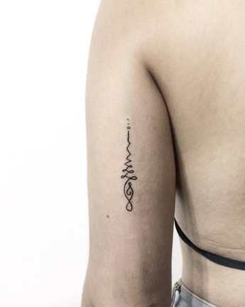 Minimalist Unalome tattoo on the upper arm, featuring a delicate spiral and dotwork design symbolizing life's journey and enlightenment.