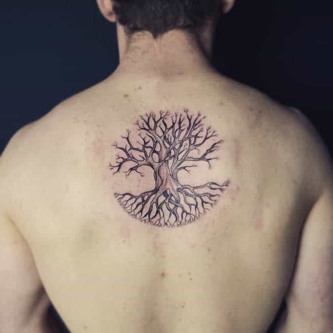 Back tattoo featuring a detailed tree of life with intertwined roots and branches forming a circular design