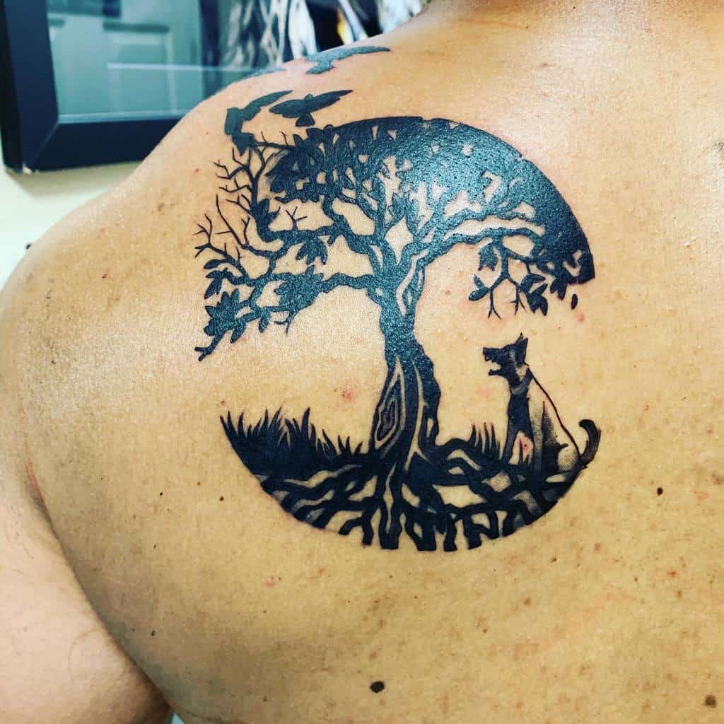 Back tattoo featuring a tree of life with detailed roots and branches, a dog sitting beneath, and birds flying above