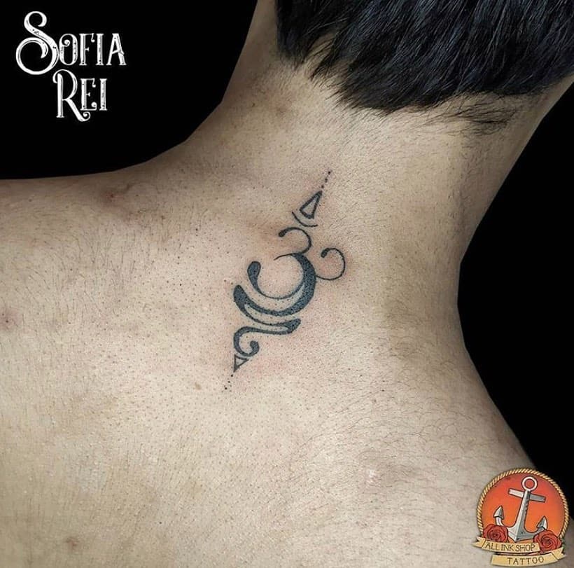 Small Om symbol tattooed on the upper back with minimalist geometric shapes and soft black shading for a subtle design