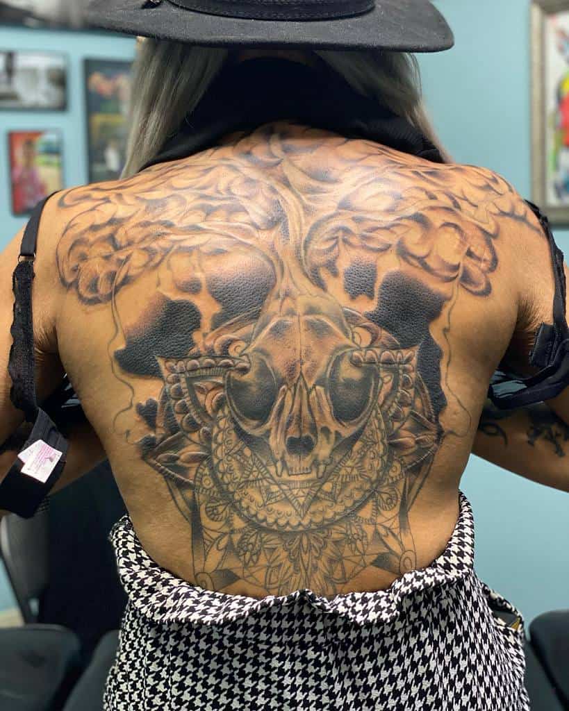 Large, detailed skull and floral tattoo on their back, featuring an intricate cat skull embedded in the design
