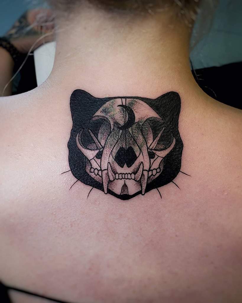 Back of neck tattoo of a cat skull blended with a crescent moon, and a cat head silhouette