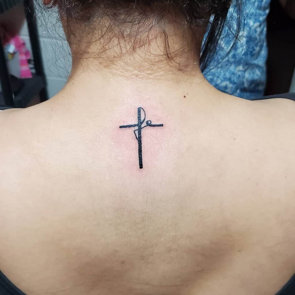 Minimalist cross tattoo on upper back with delicate script detail, beautifully symbolizing faith
