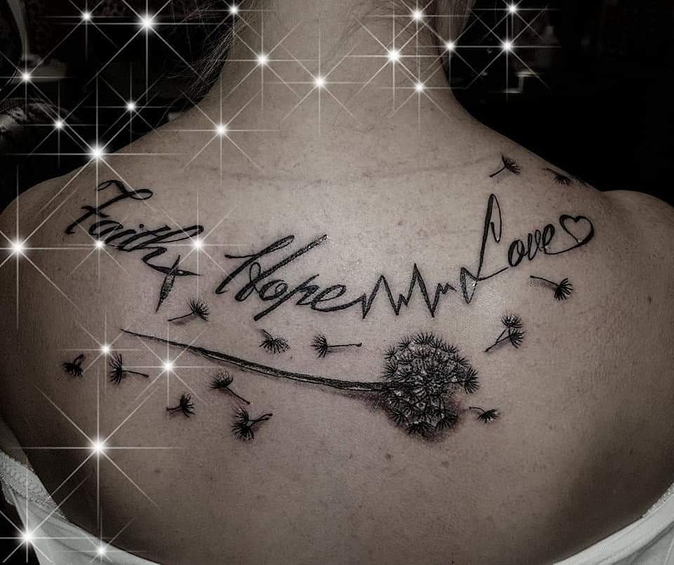 Faith, Hope, Love tattoo on the upper back with a dandelion blowing in the wind and a heartbeat line connecting the words, symbolizing life's fleeting yet beautiful moments