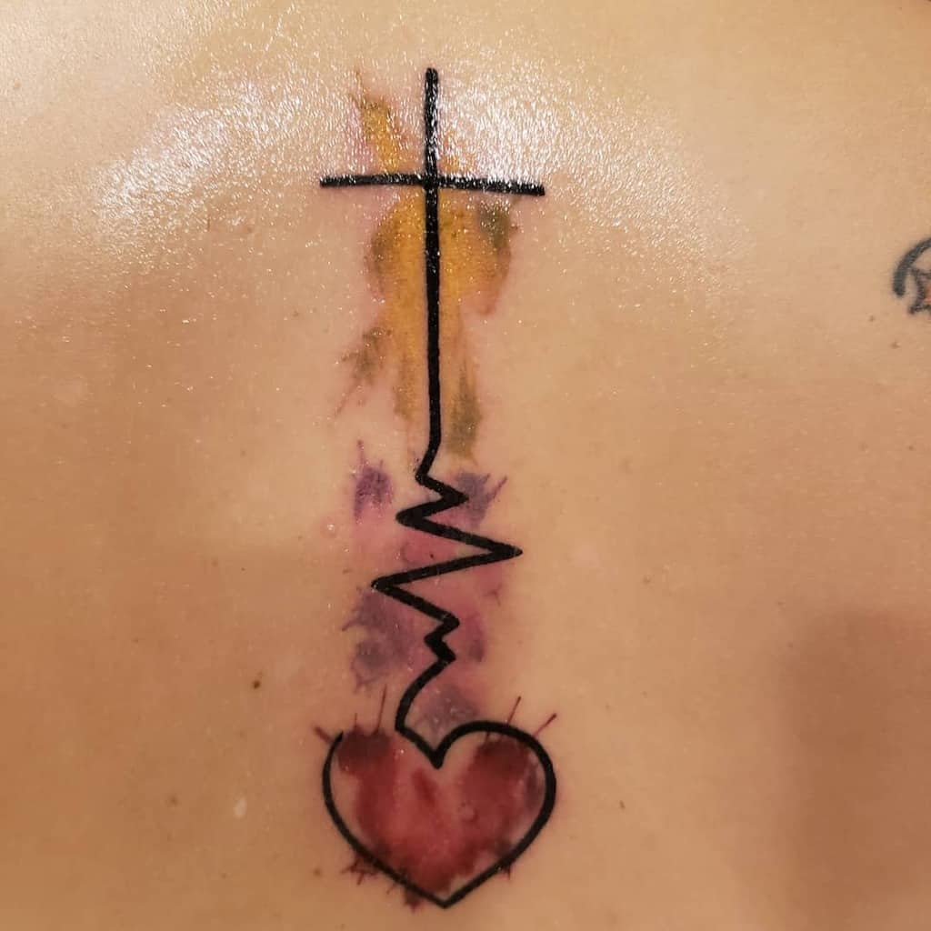 Tattoo of a cross, heartbeat line, and heart with a watercolor splash background