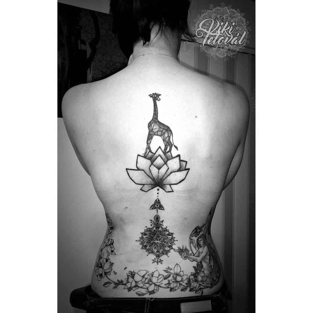 Tattooed woman's back with a giraffe, lotus, geometric design, and floral patterns