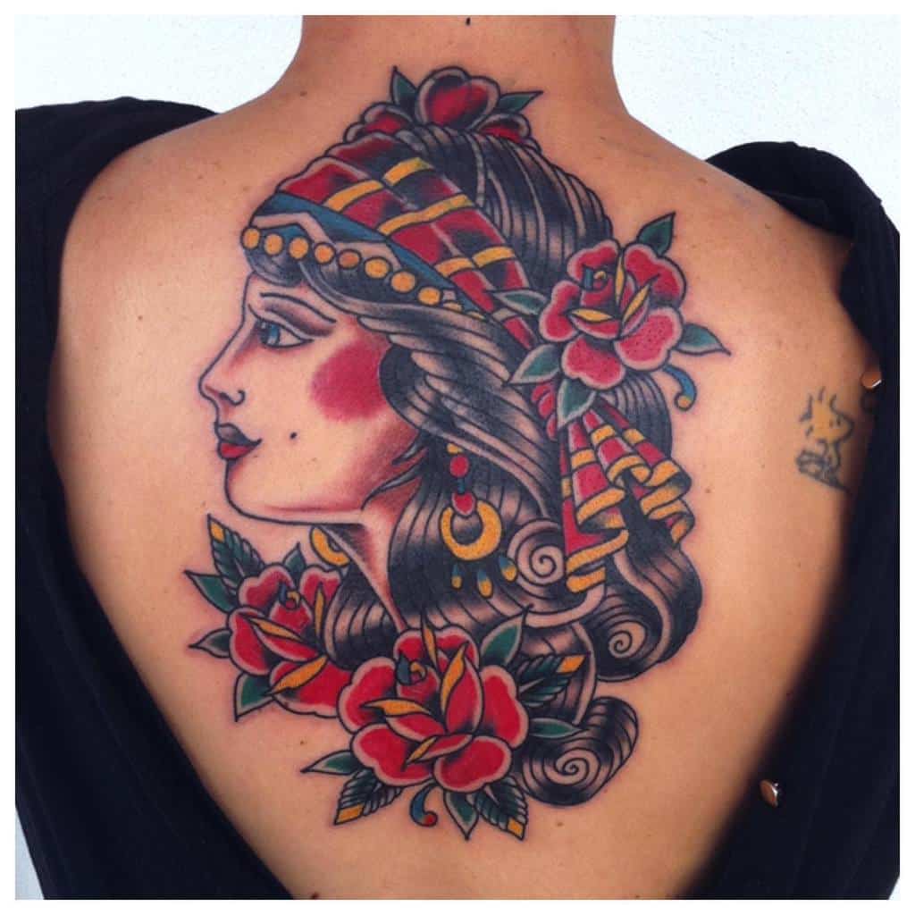 Back tattoo of a gypsy woman in a headscarf adorned with roses and intricate decorative patterns